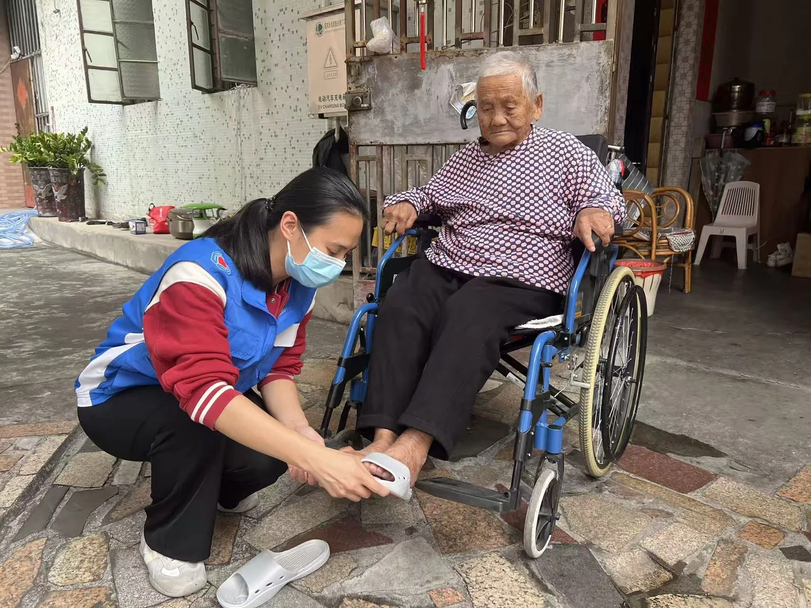 志愿者协助坐轮椅长者试穿防滑拖鞋
